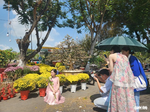 Giá hoa Tết giảm nhưng sức mua cũng... giảm theo- Ảnh 5. Trong lúc nhà vườn rầu vì hoa bán chậm, giới trẻ ra chợ hoa chụp hình lưu niệm những khoảnh khắc ngày xuân - Ảnh: BỬU ĐẤU