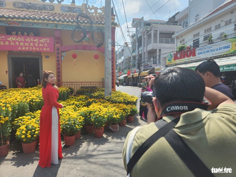 Giá hoa Tết giảm nhưng sức mua cũng... giảm theo- Ảnh 7. Giới trẻ diện áo dài chụp hình lưu niệm tại chợ hoa xuân đường Phạm Hồng Thái, phường Mỹ Long, TP Long Xuyên - Ảnh: BỬU ĐẤU