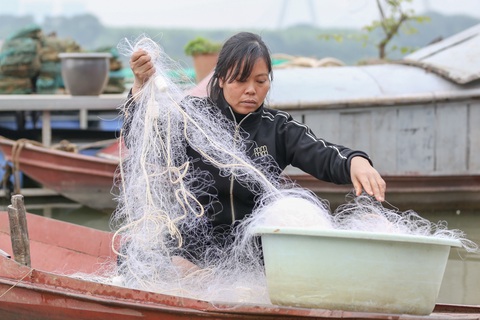 Chị Hiếu, một ngư phủ dạn dày kinh nghiệm, tranh thủ đan lại tấm lưới đánh cá bị rách hôm trước - Ảnh: HÀ QUÂN Chị Hiếu, một ngư phủ dạn dày kinh nghiệm, tranh thủ đan lại tấm lưới đánh cá bị rách hôm trước - Ảnh: HÀ QUÂN