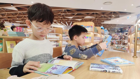 'Lì xì' Tết sớm cho con trong nhà sách- Ảnh 5. Bé Nguyễn Khánh Kiệt (7 tuổi) say sưa ngồi đọc sách. “Con rất thích được đi nhà sách, bởi vì ở đây có nhiều truyện con thích đọc”, Khánh Kiệt nói.