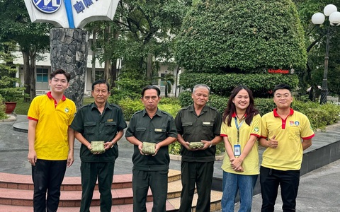 Sinh viên gói bánh chưng tặng chú bảo vệ, cô lao công- Ảnh 1. Các chú bảo vệ của trường nhận chiếc bánh chưng "mới ra lò" của sinh viên - Ảnh: UFM
