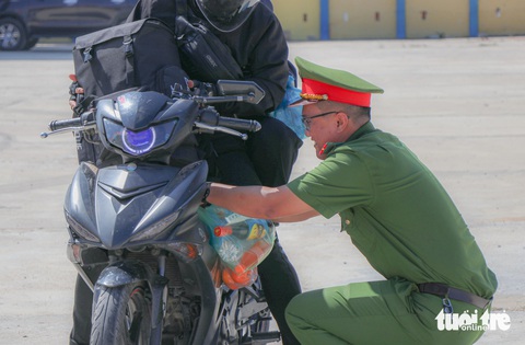 Về quê ăn Tết, bất ngờ thấy công an gọi vào, ngờ đâu được tặng quà- Ảnh 2. Do nhiều đồ trên xe, người dân không thể tự treo quà nên công an huyện Thuận Nam đã hỗ trợ để người dân tham gia giao thông an toàn - Ảnh: DUY NGỌC