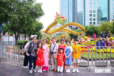 Ba linh vật rồng trên đường hoa Nguyễn Huệ khoe dáng- Ảnh 1. Nhiều gia đình "du xuân" sớm đã đứng chụp lưu niệm trước đường hoa. Hình ảnh rồng lượng bay cao ở cổng kết "Nhất Đại Thăng Long" giúp người dân có thể ngắm nhìn từ xa.
