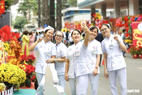 Ở đường hoa Bệnh viện Chợ Rẫy có Tết, có tình thương- Ảnh 2. Các điều dưỡng, y tá của bệnh viện tranh thủ ghé đường hoa chụp ảnh lưu niệm trước khi vào ca trực - Ảnh: PHƯƠNG QUYÊN