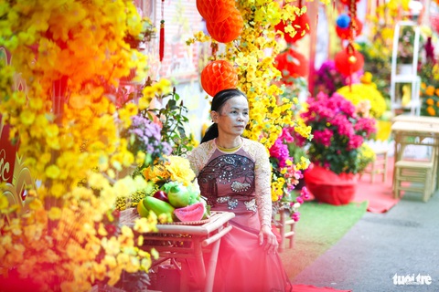 Ở đường hoa Bệnh viện Chợ Rẫy có Tết, có tình thương- Ảnh 12. Sau một hồi dạo quanh đường hoa, cô Nguyễn Thị Tiền (quê Tây Ninh) cũng can đảm chọn cho mình một chiếc áo dài và nhờ thợ chụp ảnh kỷ niệm. "Kệ, đường hoa đẹp thế này mà sao mình phải ngại. Cứ chụp đi đã, quan trọng là vui, cô nói.