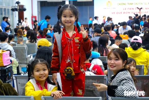 Hàng chục ngàn lao động về quê ăn Tết trên những chuyến tàu, chuyến xe mùa xuân- Ảnh 1. Hai chị em Mỹ Tuyền, Phương Nghi (quê Thừa Thiên Huế) háo hức khi lần đầu tiên đến ga Sài Gòn đi tàu với cha mẹ về quê ăn Tết. Chị Nguyễn Thị Mùi - mẹ của hai bé - đã làm việc tại Công ty Paiho (quận Bình Tân) 9 năm - Ảnh: VŨ THỦY