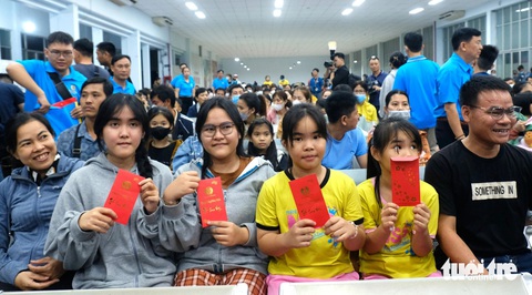 Hàng chục ngàn lao động về quê ăn Tết trên những chuyến tàu, chuyến xe mùa xuân- Ảnh 2. 4 người con của chị Lê Thị Hiền (41 tuổi, quê Thừa Thiên Huế) với niềm vui nhận lì xì từ Liên đoàn Lao động TP.HCM trước khi theo cha mẹ lên tàu về quê ăn Tết. Chị Huyền đã 15 năm làm công nhân tại TP.HCM - Ảnh: VŨ THỦY