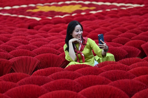 Du khách chụp ảnh selfie trước những bó hương xếp hình quốc kỳ Việt Nam ở làng Quảng Phú Cầu, ngoại ô Hà Nội, ngày 20-1 - Ảnh: AFP Du khách chụp ảnh selfie trước những bó hương xếp hình quốc kỳ Việt Nam ở làng Quảng Phú Cầu, ngoại thành Hà Nội, ngày 20-1 - Ảnh: AFP