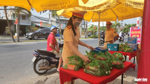 Lập 'trạm dừng chân nghĩa tình' phát nước, sữa cho bà con trên đường về quê- Ảnh 3. "Trạm dừng chân nghĩa tình" do Phòng cảnh sát giao thông Công an tỉnh An Giang lập ven quốc lộ 91, đoạn gần cổng chào TP Long Xuyên - Ảnh: BỬU ĐẤU