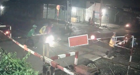 Xem những pha nhân viên đường sắt cứu người tông văng chắn khi tàu sắp đến- Ảnh 3. Người dân, anh tài xế Grap đến hỗ trợ cùng nhân viên gác chắn. Còn một nhân viên gác chắn cầm đèn ra tín hiệu cảnh báo cho lái tàu biết đang có chướng ngại vật - Ảnh: Cắt từ camera