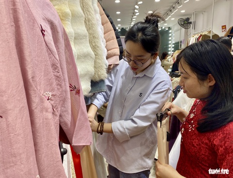 Giới trẻ Hà Nội đổ xô săn sale, tràn ra đường đêm cuối năm- Ảnh 2. Tối 27 tháng chạp, các bạn trẻ hào hứng sắm sửa cho mình bộ áo dài để đón năm mới đang đến rất gần - Ảnh: HÀ THANH