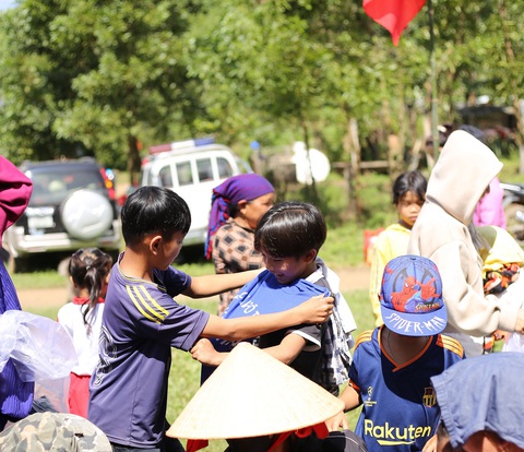 Cõng Tết lên non, vất vả mang Tết đến nơi không điện, không sóng di động- Ảnh 1. Hai em nhỏ ướm cho nhau bộ quần áo mà các cô chú miền xuôi mang lên - Ảnh: TRẦN MAI
