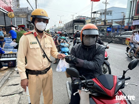 Cảnh sát giao thông phát nước, khăn lạnh miễn phí cho người dân về quê ăn Tết- Ảnh 1. Cảnh sát giao thông phát nước suối miễn phí cho người dân về quê ăn Tết - Ảnh: HOÀI THƯƠNG