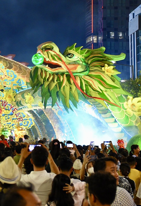 Người dân 'săn rồng' trên đường hoa Nguyễn Huệ 2024- Ảnh 6. Khách sử dụng điện thoại "săn rồng" trên app do ban tổ chức cung cấp. Đây là hoạt động tăng thêm trải nghiệm trên đường hoa Nguyễn Huệ 2024.