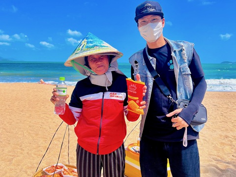 Mang niềm vui ngày Tết qua những nét vẽ- Ảnh 1. Cụ bà bán hàng rong vui thích khi nhận chiếc nón vẽ tay của anh Chiến - Ảnh: THANH CHƯƠNG