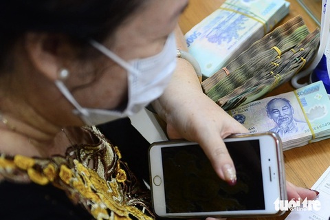 Mất sạch tiền Tết trong tài khoản ngân hàng vì bị chiếm quyền điện thoại mà không biết- Ảnh 1. Nhóm tội phạm có xu hướng chiếm đoạt tài sản, qua việc chiếm quyền truy cập thiết bị di động của người dân. Trong ảnh: khách hàng giao dịch tại ngân hàng - Ảnh: QUANG ĐỊNH
