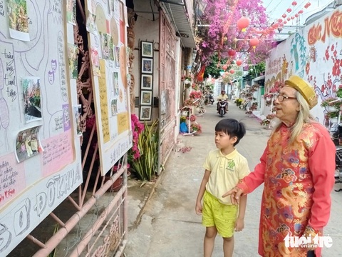 Phố 'Ông Đồ' điểm du xuân lý tưởng, tái hiện Tết xưa ở miền Tây- Ảnh 3. Một em nhỏ thích thú khi được ông Đồ Hoàng Anh nói về con đường bích họa - Ảnh: HOÀI THƯƠNG