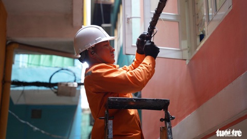 Tháng thanh niên 2024: Cùng hướng tới đô thị văn minh- Ảnh 1. Thợ điện trẻ hỗ trợ bó gọn dây cáp điện trong hẻm trên đường Nguyễn Thái Học (quận 1, TP.HCM) - Ảnh: K.ANH