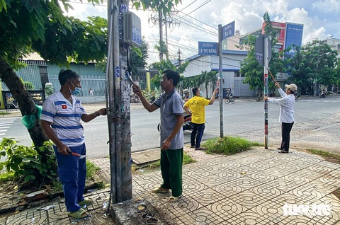 Cả phường ở TP.HCM cùng chung tay bóc quảng cáo dán bậy- Ảnh 1. Người dân phường Thới An (quận 12) hưởng ứng phong trào bóc, tẩy các quảng cáo sai quy định (do nạn dán vẽ bậy gây ra) - Ảnh: GIAI THỤY