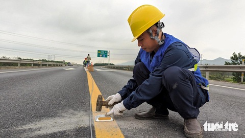 Lắp đinh phản quang, trụ cảnh báo nguy hiểm trên cao tốc Cam Lộ - La Sơn- Ảnh 2. Công nhân lắp đinh phản quang trên vạch kẻ đường phân cách hai đoạn đường xe chạy trên cao tốc Cam Lộ - La Sơn - Ảnh: N.L.