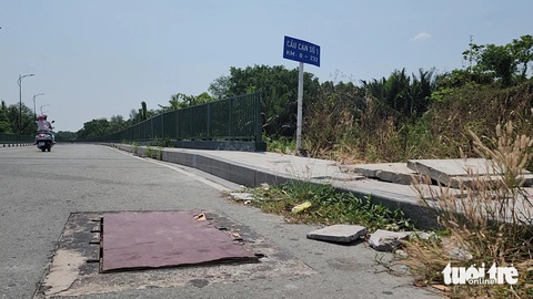 Hàng chục nắp che cột đèn trong khu đô thị Thủ Thiêm bị mất trộm- Ảnh 6. Nắp cống bằng sắt ngang khoảng 0,5m, dài khoảng 1m trên tuyến đường Bùi Thiện Ngộ bị mất cắp, cơ quan chức năng phải đậy tạm bằng tấm gỗ - Ảnh: MINH HÒA