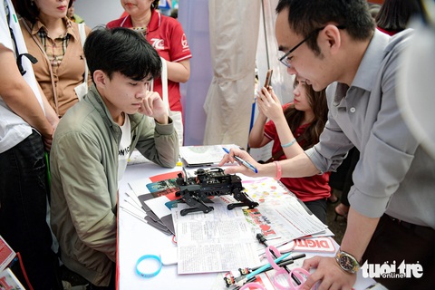 Thầy cô và sinh viên trường Cao đẳng Du lịch Hà Nội mang Thầy cô Học viện Bưu chính viễn thông đang giới thiệu và tư vấn cho thí sinh về những ngành đào tạo của trường - Ảnh: NAM TRẦN