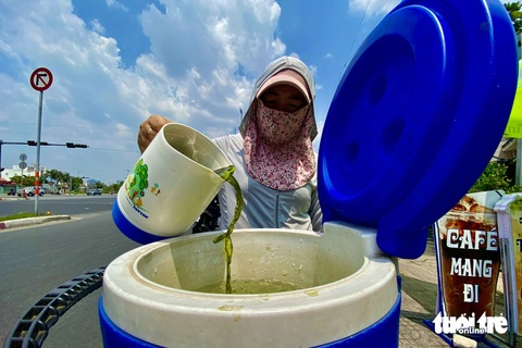 Người dân TP.HCM vật vã chống nắng, mát lòng với bình nước ven đường- Ảnh 7. Tại đường Phạm Văn Đồng, TP Thủ Đức, người phụ nữ pha trà xanh cùng đá phục vụ miễn phí người đi đường giải khát dưới cái nắng lên tới 37 độ C