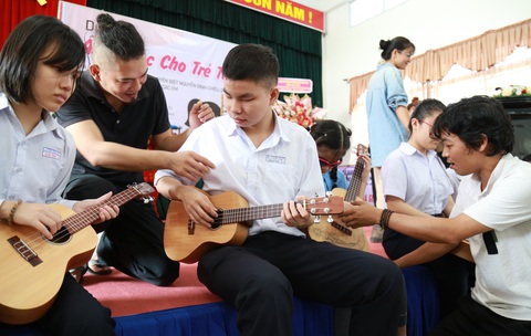 Gieo âm nhạc vào tâm hồn trẻ khiếm thị- Ảnh 1. Anh Lương Hy (phải) và anh Bửu Thăng (thứ hai, từ trái sang) dạy các em khiếm thị làm quen với đàn