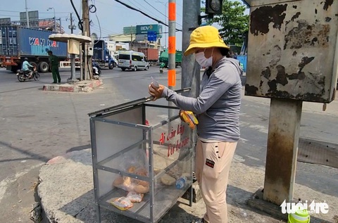 Thương quá chiếc tủ 'ai cần lấy, dư bỏ vào' ở Hóc Môn- Ảnh 1. Trong lúc đi bán vé số dạo, chị Lâm Thị Thu Tuyết (quê Sóc Trăng) lấy hai gói mì trong chiếc tủ có dòng chữ 'ai cần lấy, dư bỏ vào' đặt gần đèn tín hiệu giao thông tại khu vực giao lộ Nguyễn Văn Bứa - quốc lộ 22 (huyện Hóc Môn) - Ảnh: NGỌC KHẢI
