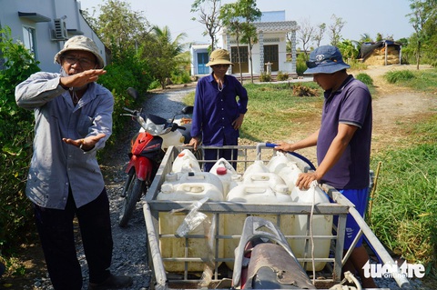 Nước kênh cạn kiệt, Tiền Giang mở 40 vòi nước công cộng miễn phí- Ảnh 1. Người dân tại huyện Tân Phú Đông tập trung tại một vòi nước công cộng miễn phí hứng về sử dụng - Ảnh: MẬU TRƯỜNG