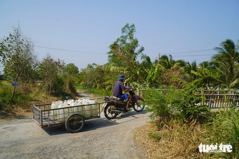 Nước kênh cạn kiệt, Tiền Giang mở 40 vòi nước công cộng miễn phí- Ảnh 2. Người dân chở nước từ vòi công cộng miễn phí về nhà để sử dụng - Ảnh: MẬU TRƯỜNG