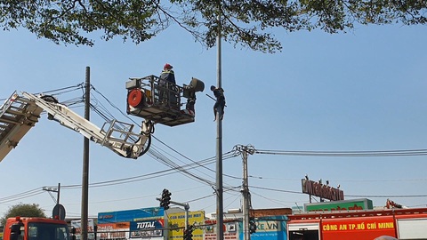 'Giải cứu' thanh niên leo lên cố thủ trên cột đèn ở quốc lộ 22- Ảnh 1. Cảnh sát dùng xe thang tiếp cận nam thanh niên đang cố thủ trên cột đèn - Ảnh: B.H.