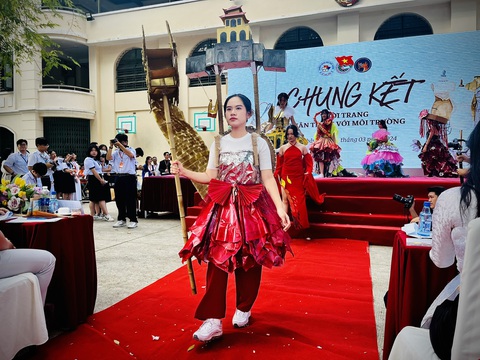 Báo cáo dự án liên môn học bằng màn trình diễn thời trang tái chế- Ảnh 8. Một bộ trang phục nữ tướng với tay cầm bảo trượng hình rồng làm bằng tre, cói, giấy và vai gánh cả Hoàng thành Thăng Long - Ảnh: MỸ DUNG