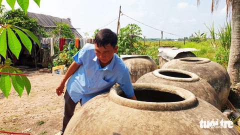 Miền Tây gấp rút tung giải pháp chống hạn, mặn ‘bủa vây’- Ảnh 3. Dù chuẩn bị nhiều lu, khạp chứa nước mưa nhưng ông Lê Văn Thành, xã Hiển Bạch, huyện Thới Bình, tỉnh Cà Mau, vẫn không đủ xài mà phải mua nước từ ghe với giá 50.000 đồng/m3 - Ảnh: THANH HUYỀN
