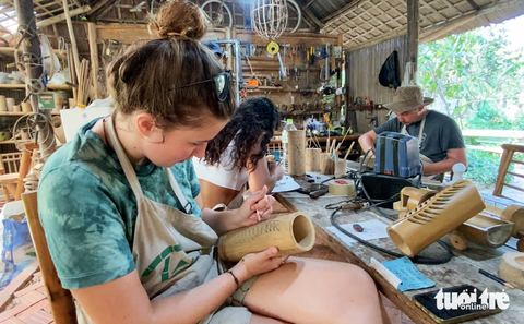 Bất ngờ những sản phẩm tinh xảo trong ngôi nhà tre độc nhất vô nhị ở Hội An- Ảnh 2. Khách du lịch trải nghiệm chế tác đồ tre - Ảnh: B.D.
