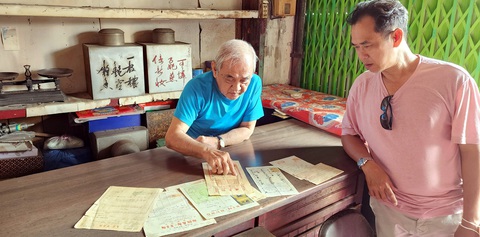 Nâng niu phố chợ Bến Thành 110 năm - Kỳ cuối: Tri ân đời phố - đời chợ - đời người- Ảnh 5. Ông Kha Minh (trái), thân nhân bà Kha Quyên ở quán trà Ô Tòng Ký, cùng anh La Hưng xem các hóa đơn, biên lai các tiệm vàng xưa trên đường Phan Chu Trinh sát chợ Bến Thành Ảnh: Phúc Tiến chụp sáng 20-3-2024
