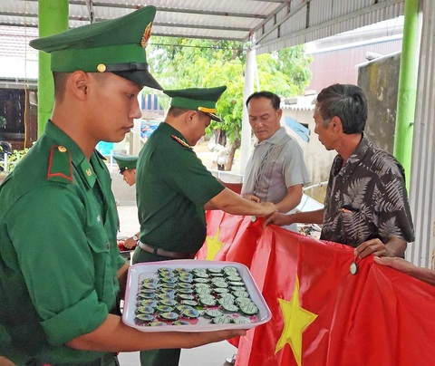 Chiếc móc khóa của đồn Hướng Lập- Ảnh 1. Cán bộ chiến sĩ Đồn biên phòng Hướng Lập tặng cờ Tổ quốc và móc khóa có in số điện thoại đường dây nóng của đồn cho bà con dân bản thuộc địa bàn đồn phụ trách - Ảnh: LÊ ĐỨC DỤC