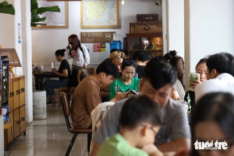 TP.HCM nắng nóng, xe cộ thưa thớt, quán cà phê máy lạnh chật ních người- Ảnh 3. Quán cà phê có máy lạnh chật ních người trên đường Lã Xuân Oai - Ảnh: NGỌC QUÝ