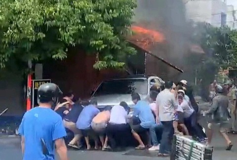 Gần 20 người hợp sức đẩy xe bán tải tránh đám cháy ở quận Tân Phú- Ảnh 1. Nhiều người hợp sức di dời ô tô bán tải thoát khỏi đám cháy - Ảnh cắt từ clip do người dân ghi lại