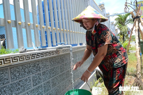 Độ mặn trên sông tăng cao, Tiền Giang mở 25 vòi nước công cộng cho bà con dùng miễn phí- Ảnh 1. Người dân các huyện phía đông tỉnh Tiền Giang dùng xô nhựa hứng nước miễn phí tại các vòi công cộng dọc đường - Ảnh: HOÀI THƯƠNG