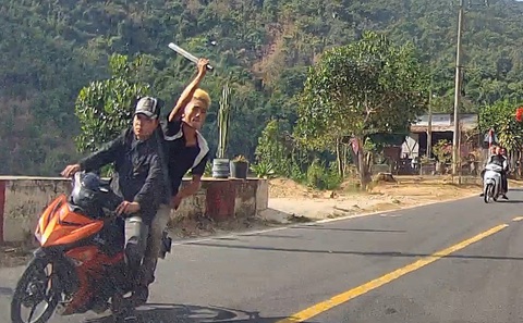 Xác định nhóm thanh niên chạy xe máy, vung mã tấu chém ô tô trên quốc lộ 55- Ảnh 1. Thanh niên ngồi sau xe máy vung mã tấu chém vào ô tô đi ngược chiều trên quốc lộ 55, huyện Hàm Thuận Bắc, Bình Thuận - Ảnh cắt từ camera hành trình
