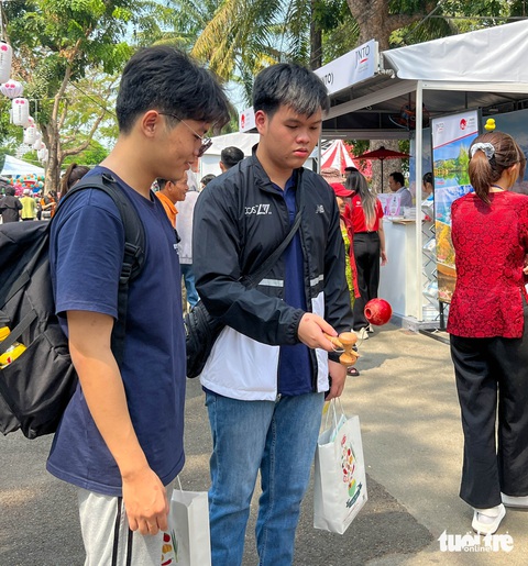 Khách tham quan trải nghiệm trò chơi dân gian Nhật Bản kendama - Ảnh: NGỌC ĐỨC Chơi trò chơi dân gian Nhật Bản kendama