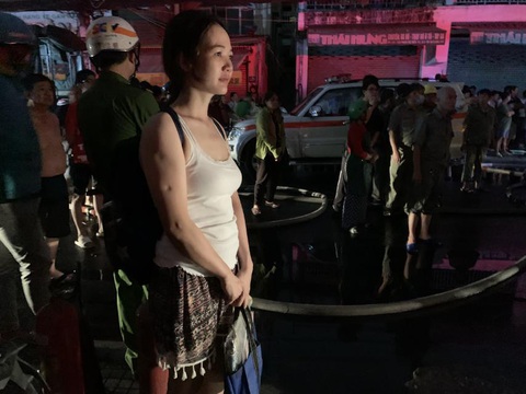 Cháy đỏ trời dãy nhà ven kênh Tàu Hủ quận 8, TP.HCM- Ảnh 7. Chị Nghĩa xách theo đồ đạc có giá trị đứng thất thần nhìn vào đám cháy, không biết nhà mình có bị ảnh hưởng không - Ảnh: PHƯƠNG NHI