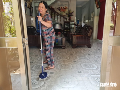 Thi công đường thổi bụi mù mịt, dân phát khóc vì dọn nhà từ sáng đến trưa- Ảnh 1. Bà Cúc khóc khi dọn nhà từ 4h sáng đến trưa vẫn chưa hết bụi bám. Bà bị gãy chân nên đi đứng khó khăn - Ảnh: TRẦN MAI