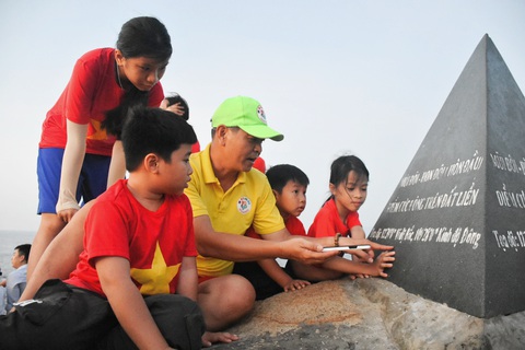 Đón bình minh sớm nhất ở Mũi Đôi cực đông đất liền bằng đường bộ- Ảnh 10. Các em nhỏ được giới thiệu về tọa độ, thông tin trên cột mốc cực Đông đất liền Tổ quốc - Ảnh: TRẦN HOÀI