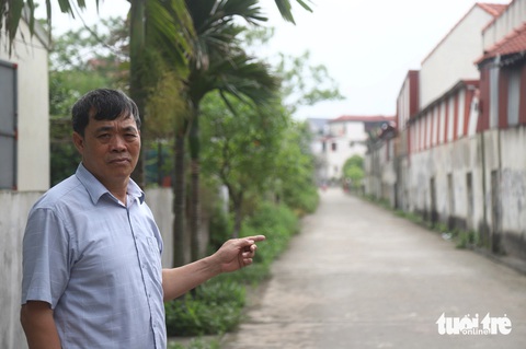 Cựu cán bộ thôn vướng án vì giao thầu đất lấy tiền làm đường, 300 người dân làm đơn xin giảm nhẹ- Ảnh 3. Ông Lê Văn Thụy chỉ về con đường làng được đổ bê tông từ nguồn tiền giao thầu đất nông nghiệp - Ảnh: DANH TRỌNG