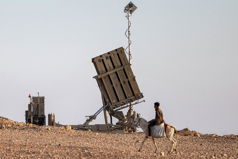 Israel tiết lộ chi phí đánh chặn 'mưa' tên lửa và drone từ Iran- Ảnh 1. Một cậu bé cưỡi lừa gần hệ thống phòng thủ tên lửa Iron Dome (Vòm sắt) của Israel tại một ngôi làng ở sa mạc Negev hôm 14-4 - Ảnh: AFP