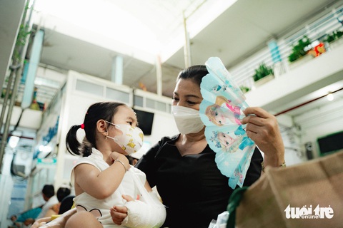 Bệnh nhân, người chăm bệnh mệt mỏi vì nắng nóng- Ảnh 5. Chị Lan (quận 5) dẫn con gái đi tái khám tại Bệnh viện Chấn thương chỉnh hình. Hơi nóng từ mái tôn phả xuống khiến hai mẹ con toát mồ hôi