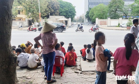 Cha mẹ đưa con lên tỉnh phản đối sáp nhập trường- Ảnh 1. Phụ huynh đưa con đến đứng trước cổng trụ sở UBND tỉnh Nghệ An để phản đối việc sáp nhập điểm trường ở xã Ngọc Sơn, huyện Thanh Chương - Ảnh: DOÃN HÒA