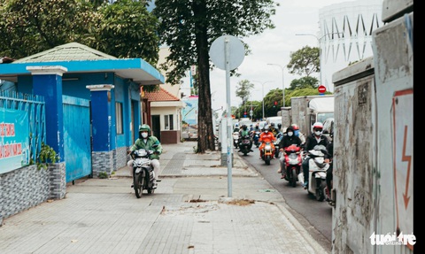 Một anh tài xế xe công nghệ hiên ngang leo lên vỉa hè trong khi những người khác đang nghiêm chỉnh chấp hành chạy xe dưới đường - Ảnh: THANH HIỆP Một tài xế xe công nghệ leo lên vỉa hè để chạy - Ảnh: THANH HIỆP